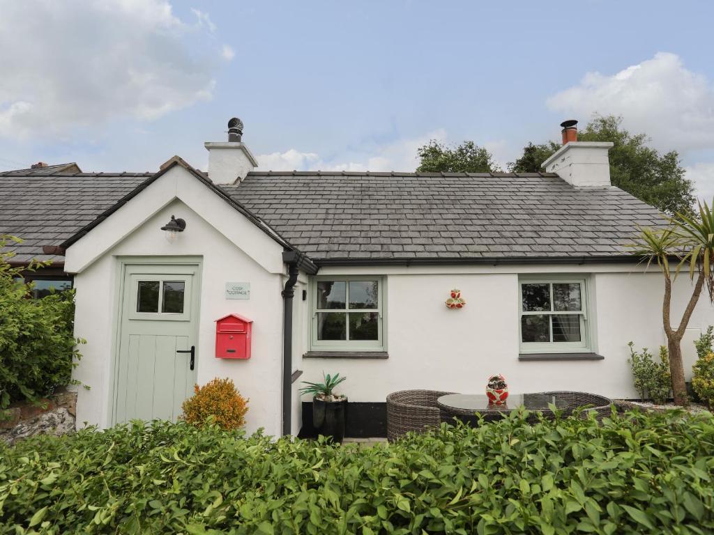 a white house with a red door at Cosy Cottage in Menai Bridge