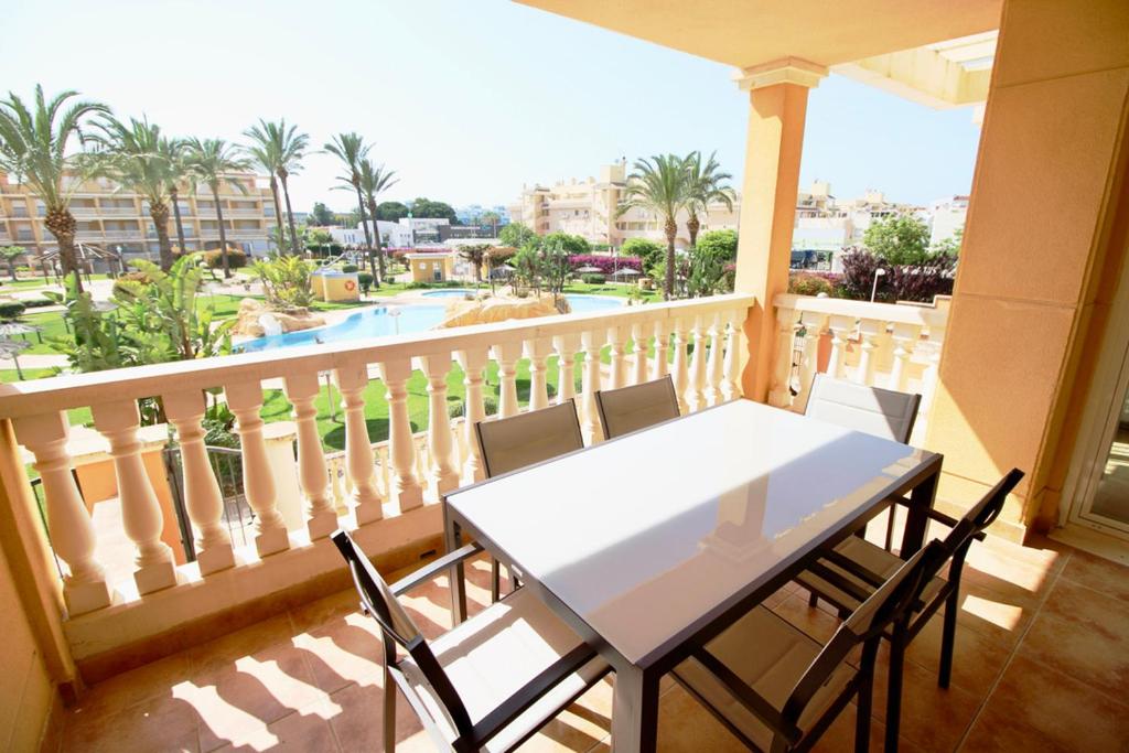 een tafel en stoelen op een balkon met uitzicht op een zwembad bij Aquamarinas 89 in Denia