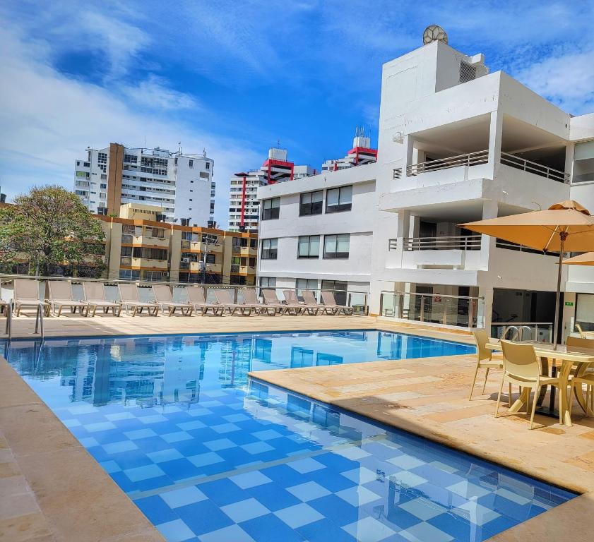 una piscina de hotel con sillas y sombrilla en Hotel Arhuaco Rodadero, en Santa Marta