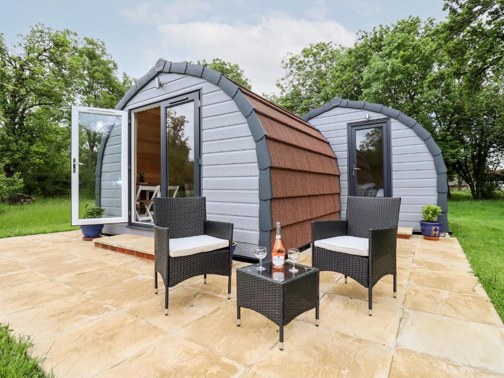 a small shed with chairs and a table on a patio at Meadow Lodge Berrys Place Farm in Gloucester