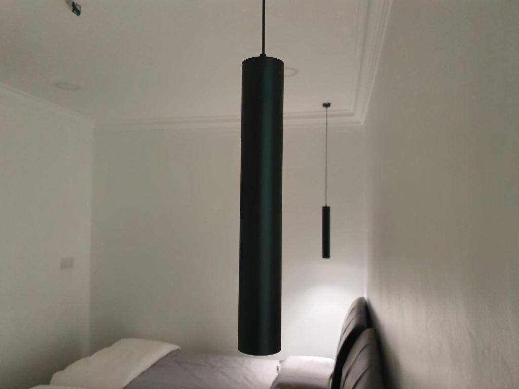 um lustre preto pendurado sobre uma cama num quarto em Number A Homestay em Raub