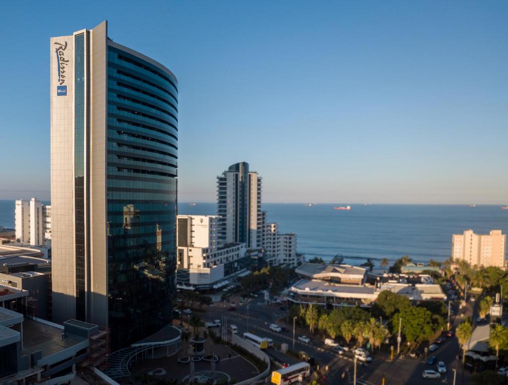 eine Skyline der Stadt mit einem hohen Gebäude und dem Meer in der Unterkunft Radisson Blu Hotel, Durban Umhlanga in Durban