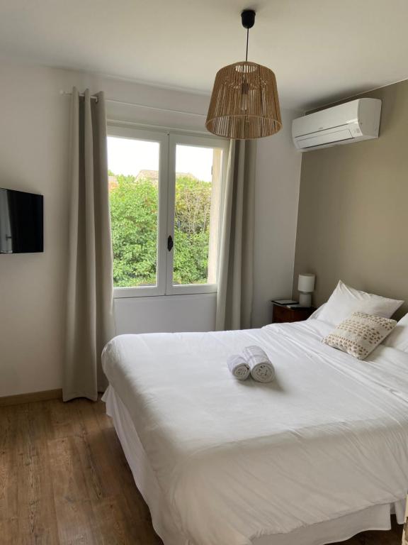 Un dormitorio con una gran cama blanca y una ventana en Le Patio, chambres d hôtes pour adultes en Camargue, possibilité de naturisme à la piscine,, en Aimargues
