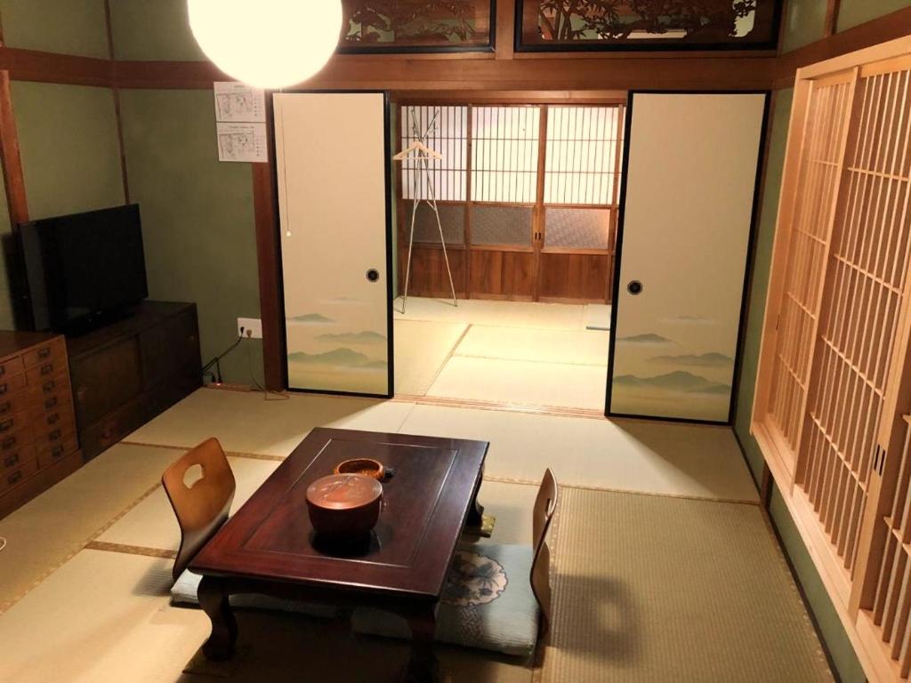 uma sala de estar com uma mesa e portas de vidro em Tomo's INN - priceless experience - em Obu