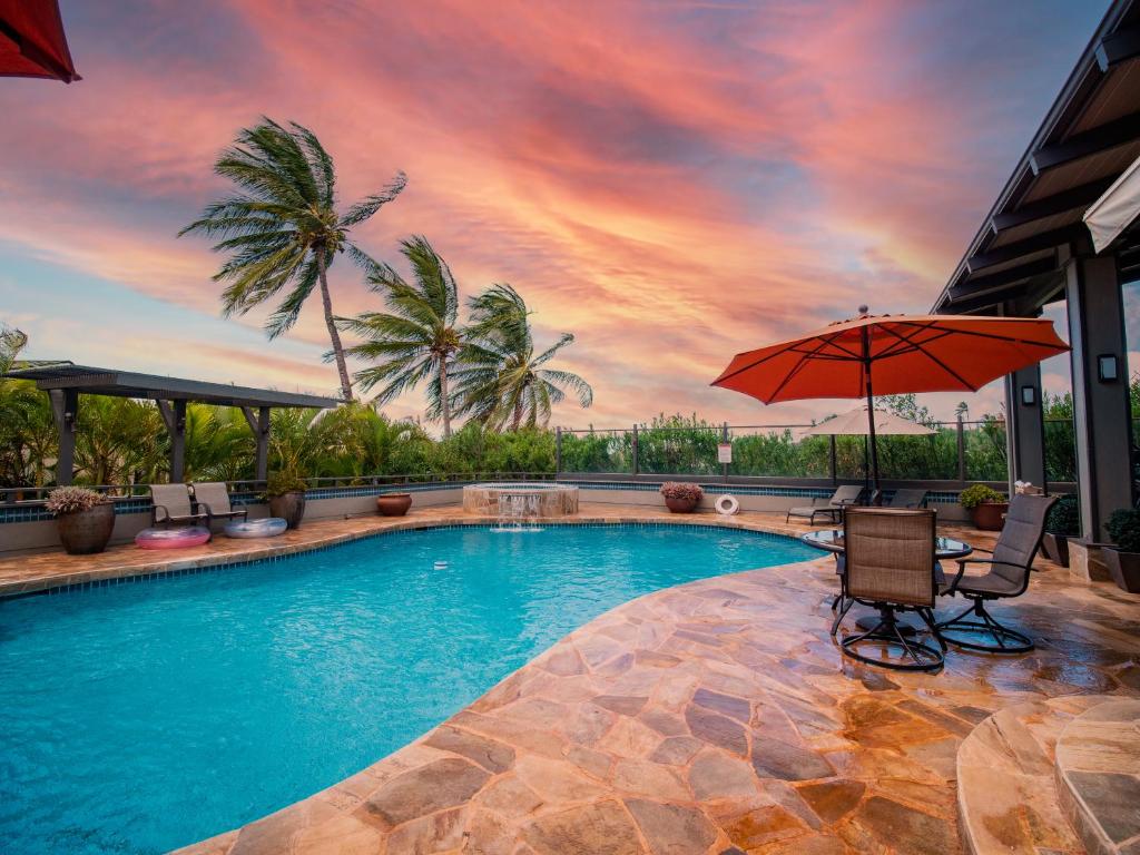 a swimming pool with two chairs and an umbrella at Noahs Hideaway Luxury B&B in Lahaina