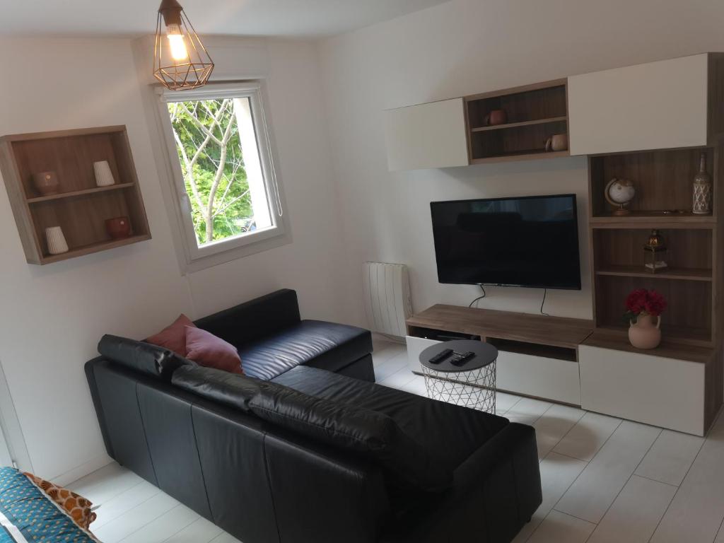 a living room with a black leather couch and a television at Home Up Bezons in Bezons