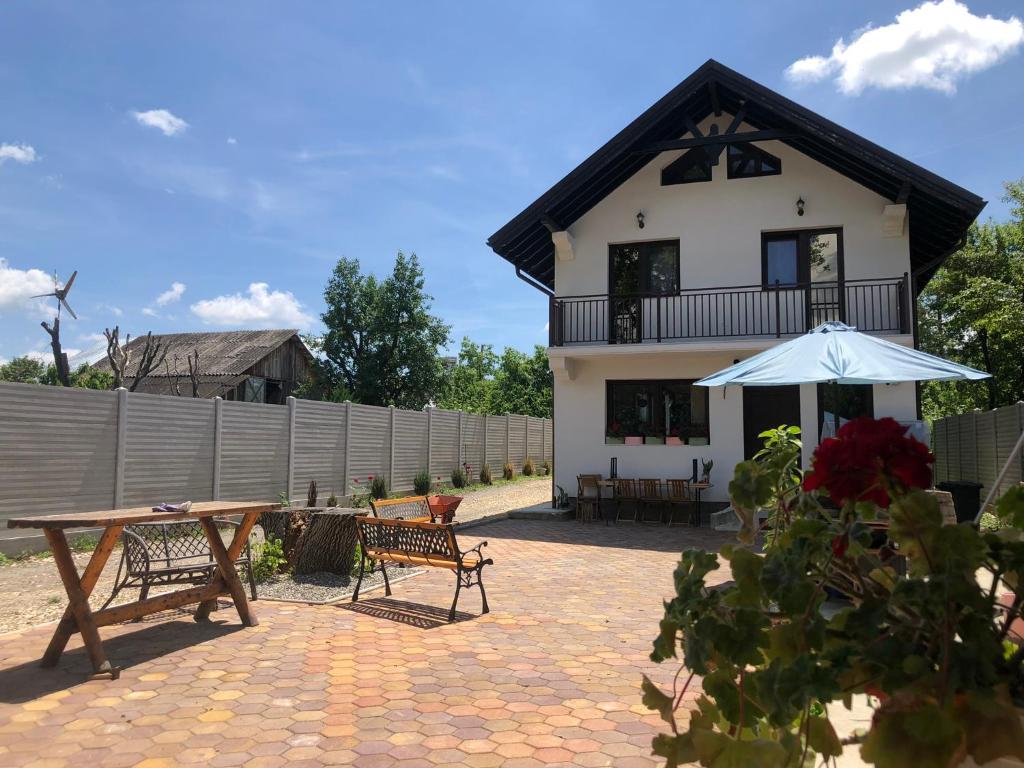 肯普隆格的住宿－Pensiunea Crețișoara，房屋前设有带桌子和遮阳伞的天井。