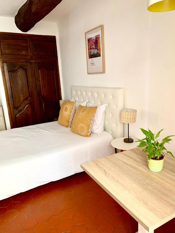 - une chambre avec un lit blanc et une table en bois dans l'établissement Le 1835, Studio Ambre-Jaune, à Moustiers-Sainte-Marie