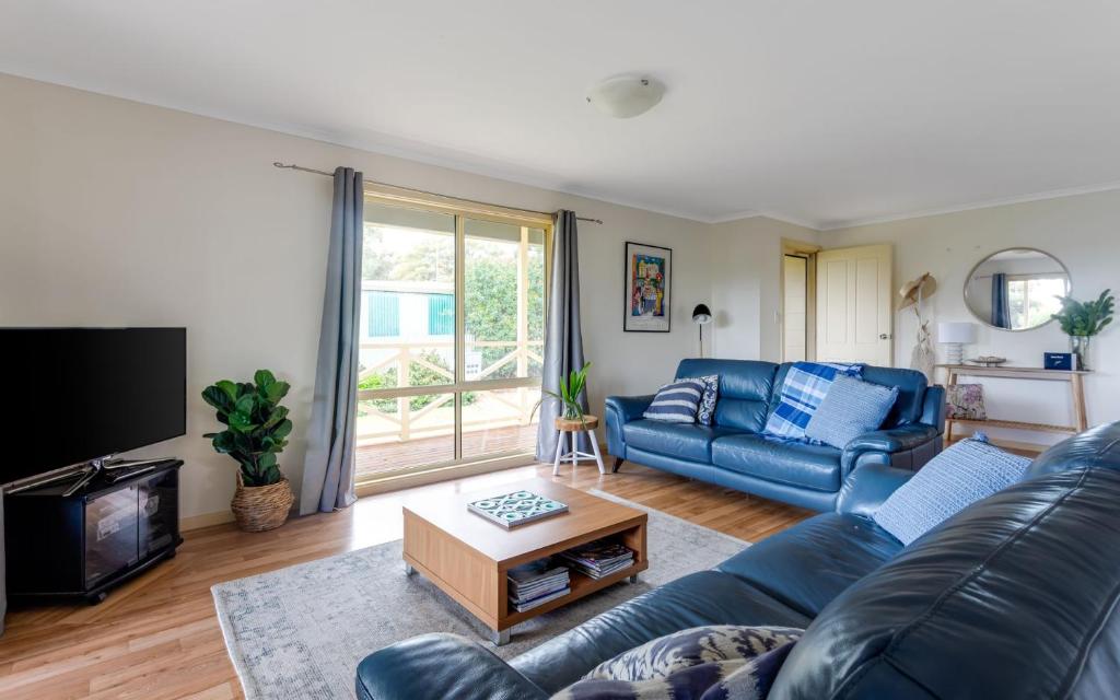 a living room with a blue couch and a tv at Carrawaves 73 LaRonde in Carrickalinga