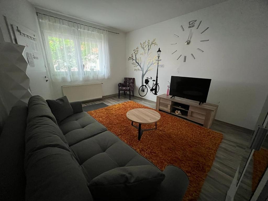 Una sala de estar con un sofá y un reloj en la pared. en Apartman Dunav - PARKING - Self check in, en Osijek