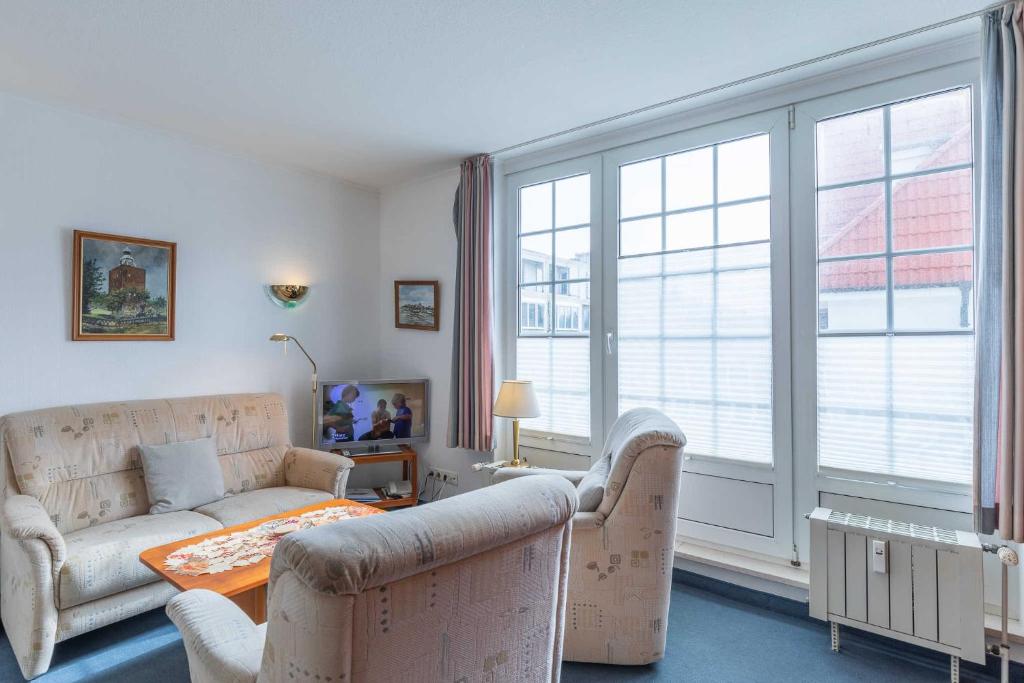 - un salon avec un canapé, une table et des fenêtres dans l'établissement Fischerhus Wohnung 4, à Cuxhaven
