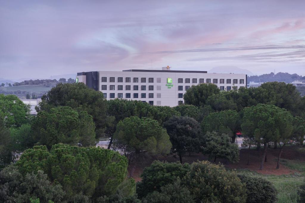 a large white building with trees in front of it at Holiday Inn Barcelona - Sant Cugat, an IHG Hotel in Sant Cugat del Vallès