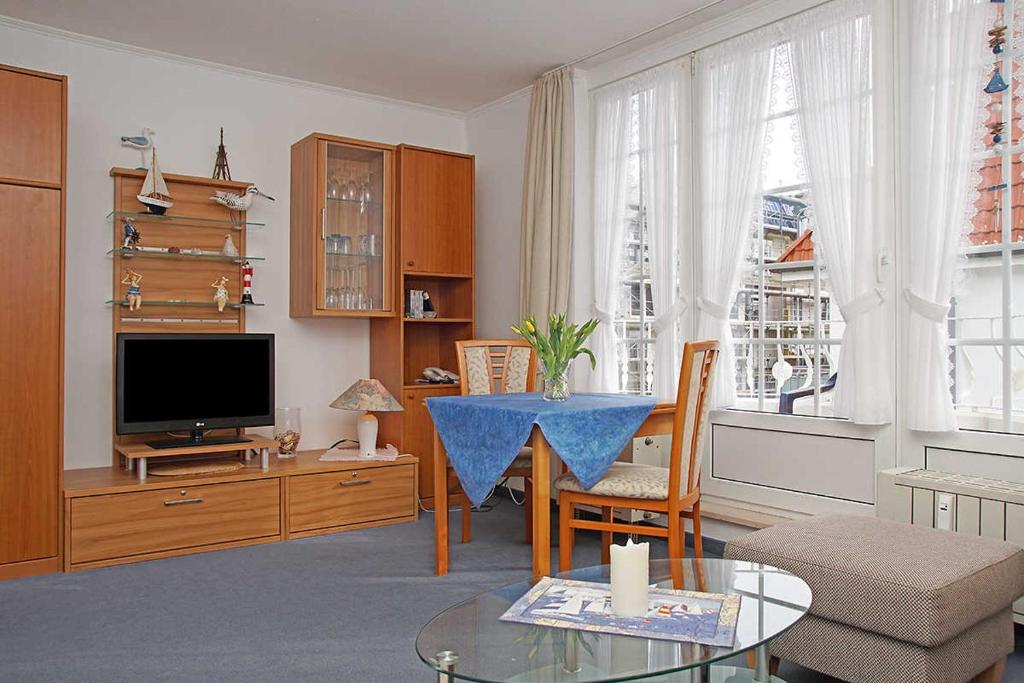 een woonkamer met een tafel en een televisie bij Fischerhus _ Wohnung 5 in Cuxhaven