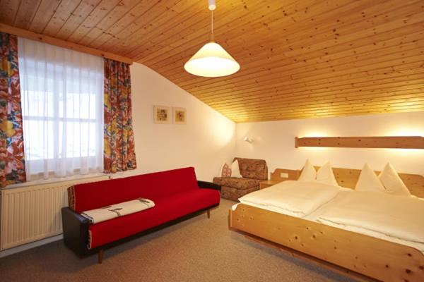 ein Schlafzimmer mit einem großen Bett und einem roten Sofa in der Unterkunft Appartment Rettenwender in Filzmoos