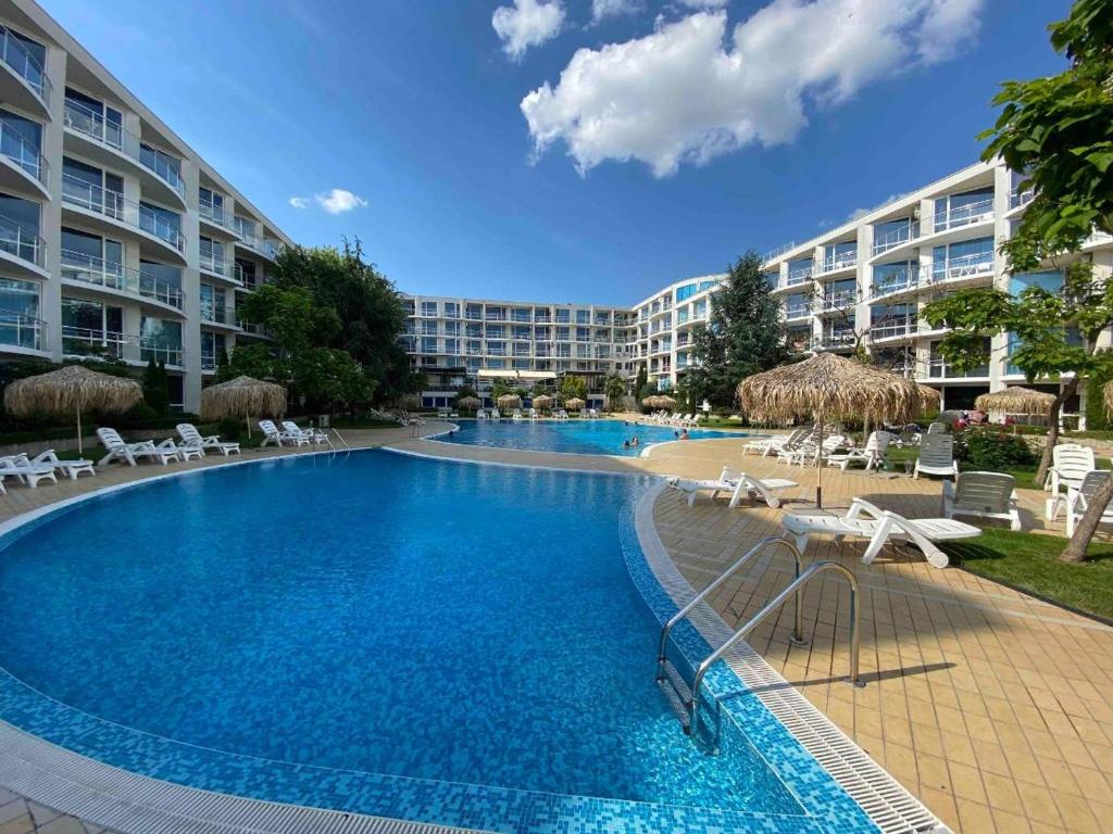 une grande piscine avec des chaises et un complexe dans l'établissement Апартамент ДЕКОР, à Bourgas