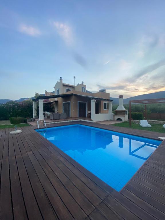 a swimming pool with a wooden deck and a house at Georges Villa Galaxidi, family, pool and garden in Galaxidi