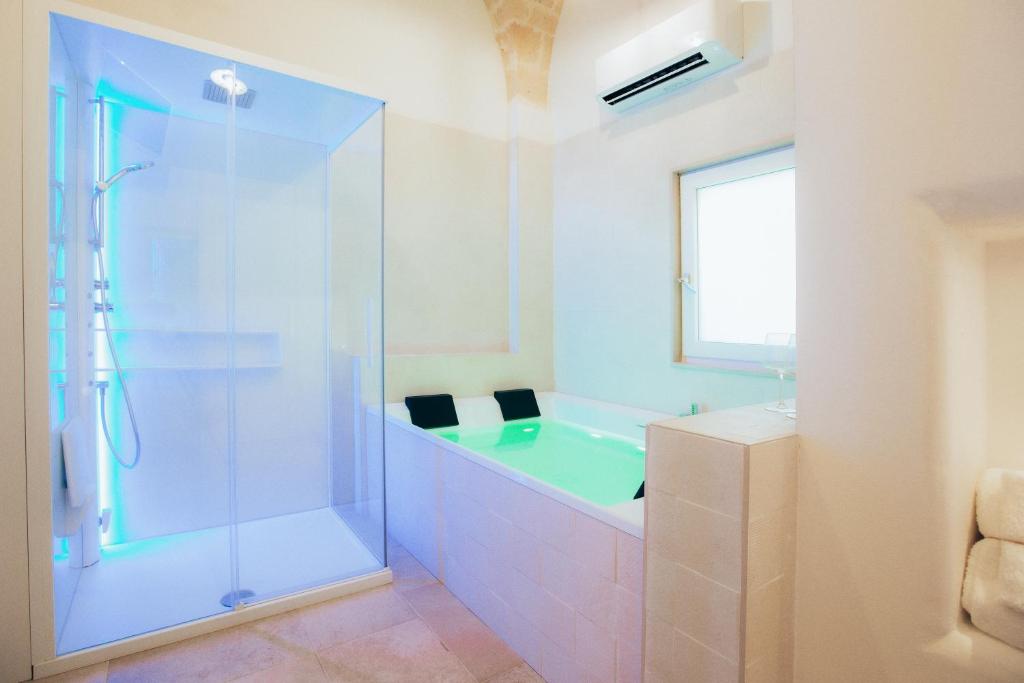 een badkamer met een bad en een glazen douche bij Filia Solis - Old Town SUITEs & SPA in Brindisi