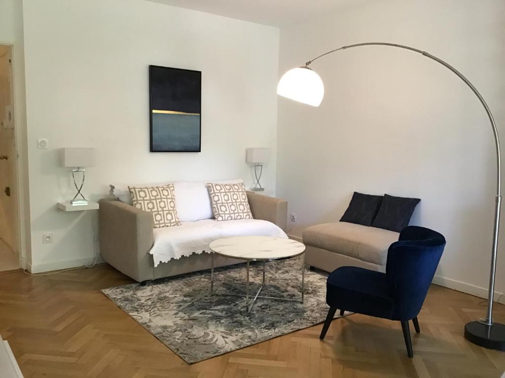 ein Wohnzimmer mit einem Sofa, einem Tisch und einem Stuhl in der Unterkunft Grand T2 5min du centre historique D'Aix en Provence in Aix-en-Provence