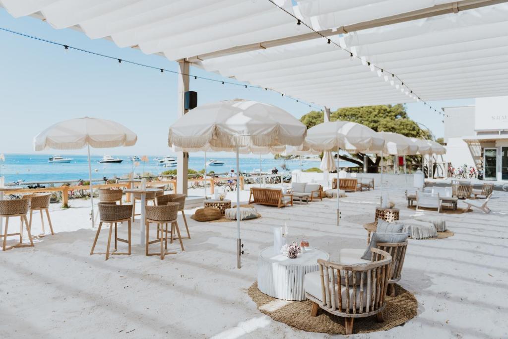 a restaurant with tables and chairs and umbrellas on the beach at Samphire Rottnest in Rottnest Island