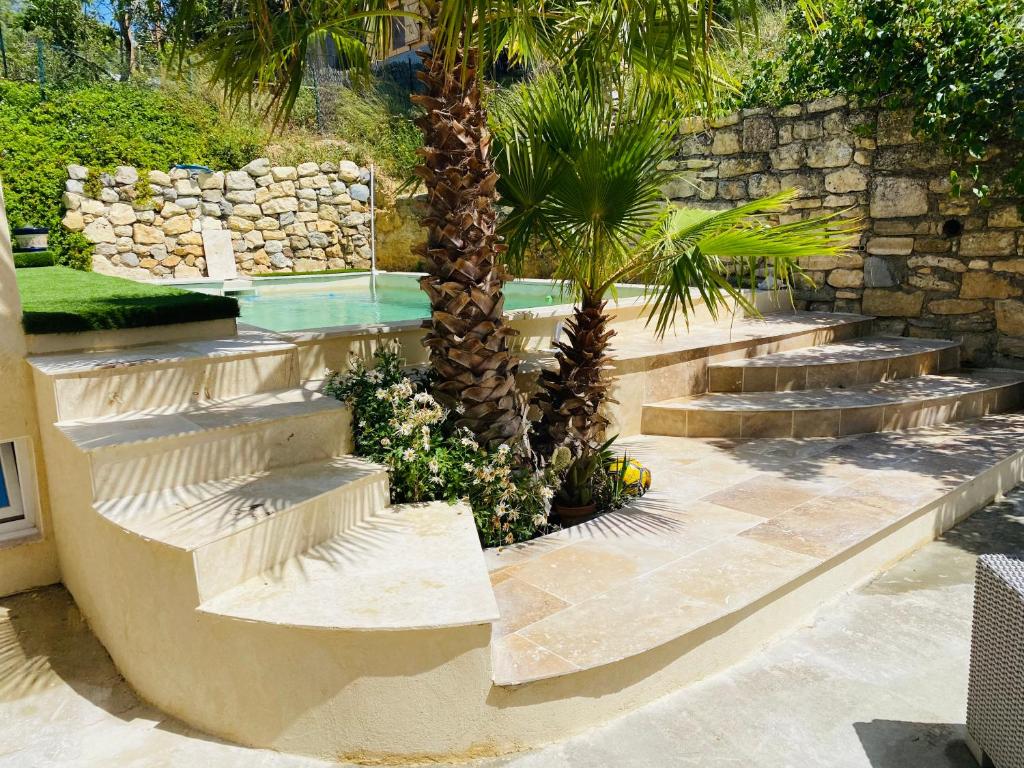 un jardin avec des escaliers, des palmiers et une piscine dans l'établissement Camin del Bosc, à Roquefort-des-Corbières