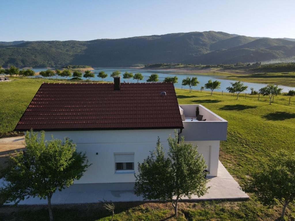 uma casa branca com um telhado vermelho e um campo verde em Vikendica Bruše em Jaklići