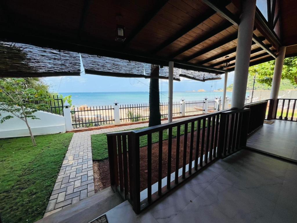 een uitzicht op het strand vanaf de veranda van een huis bij Janas Blue Water Corner in Trincomalee