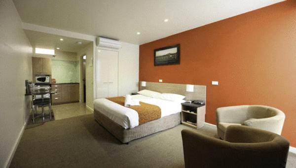 a hotel room with a bed and two chairs at Mansfield Motel in Mansfield