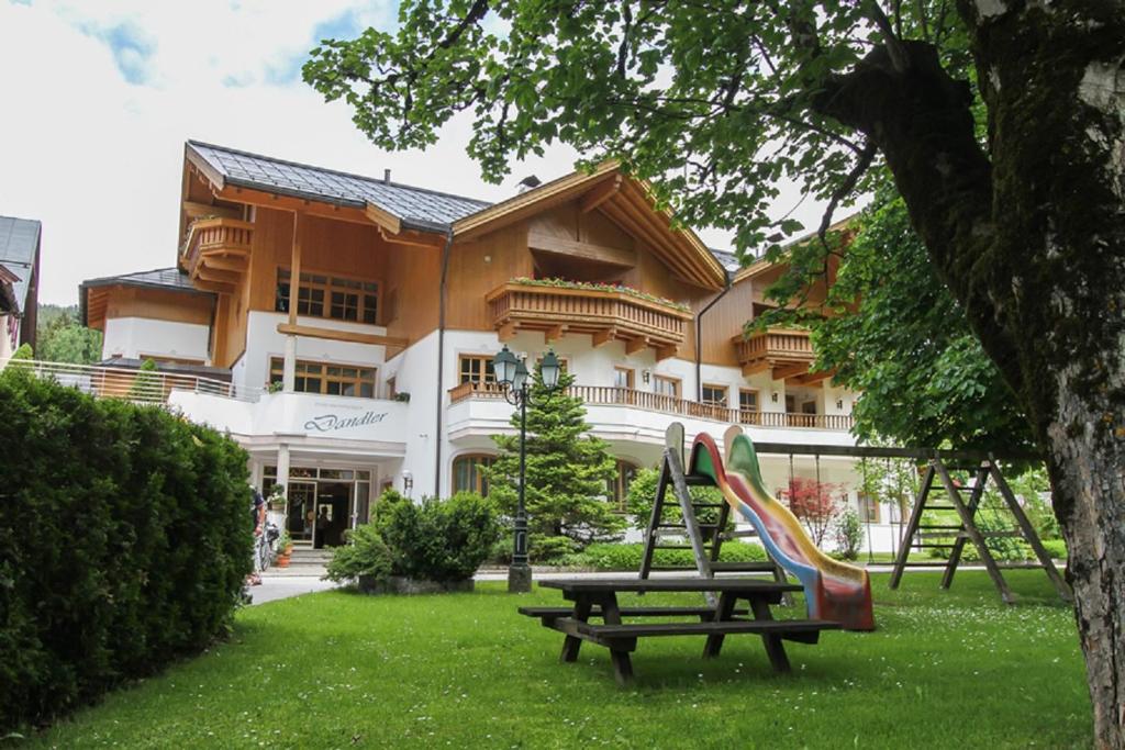 un parque con un tobogán frente a un edificio en Dandler - Zimmer und Ferienwohnungen, en Fieberbrunn