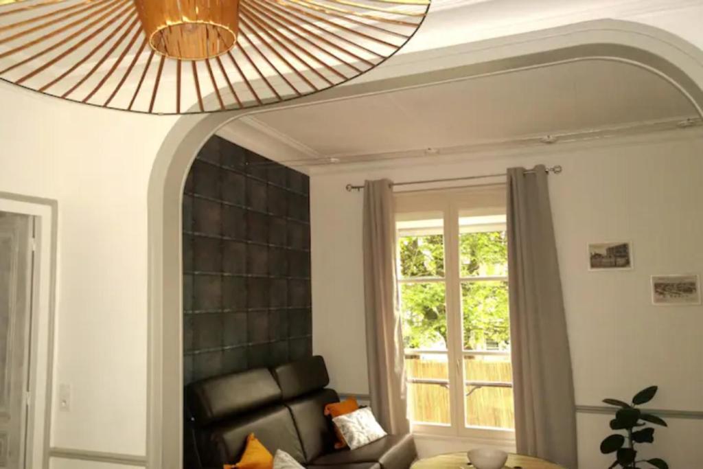 a living room with a black leather couch and a window at Le clos des maraîchers in Sainte-Savine