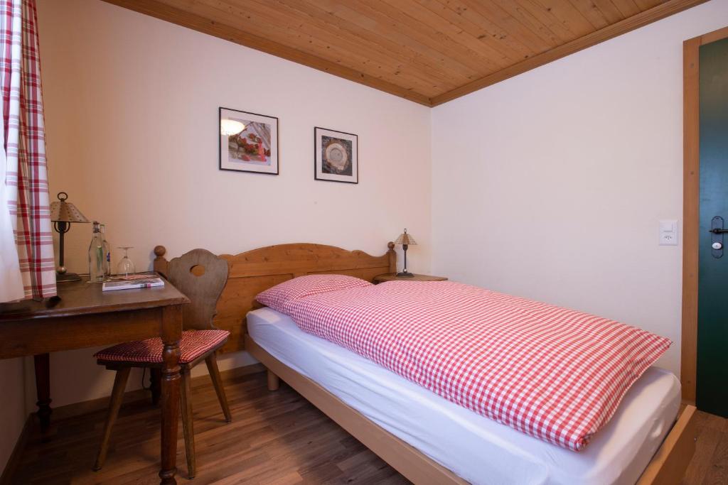 a bedroom with a bed with a red and white blanket at Hotel Bären in Gsteig