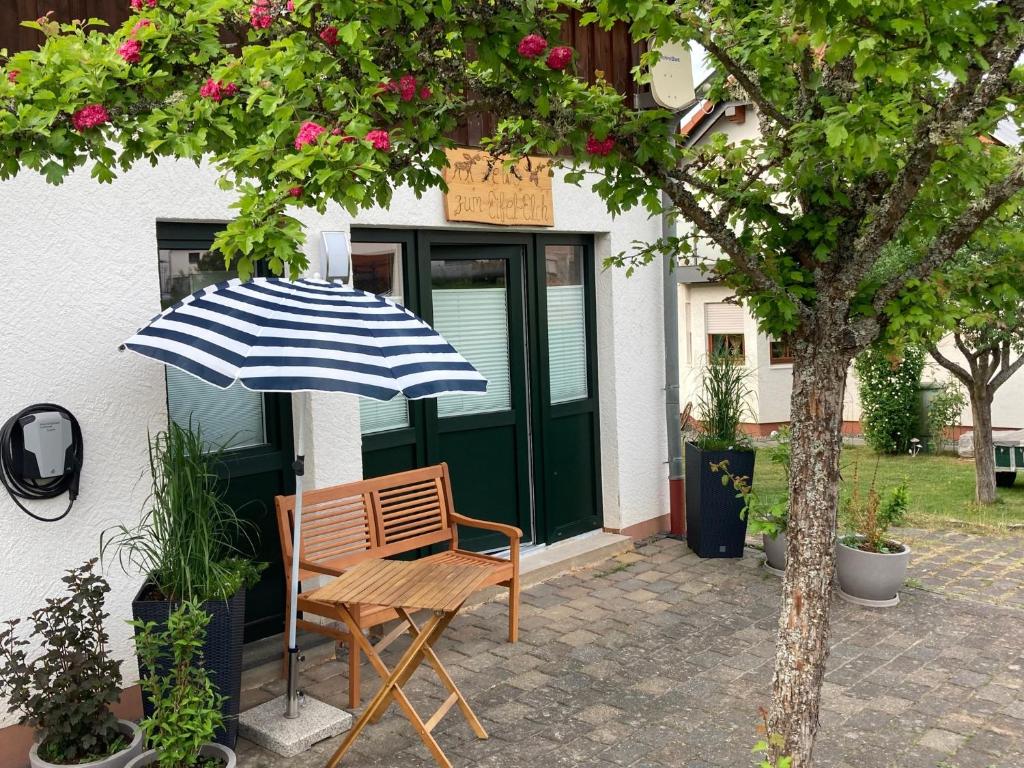 a wooden chair and an umbrella in front of a building at Ferienwohnung Zum Eifelelch in Daun