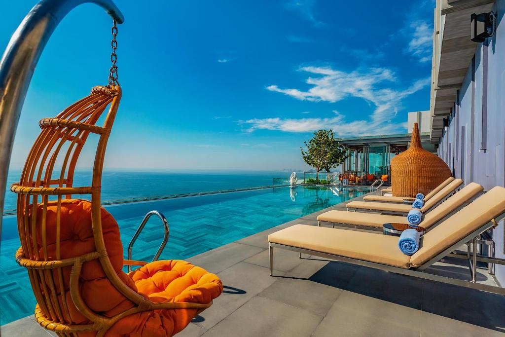 a resort pool with lounge chairs and the ocean at Le Sands Oceanfront Danang Hotel in Danang