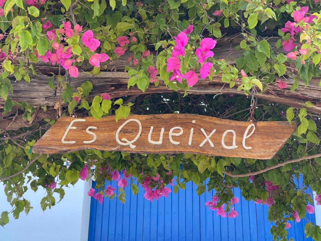 a sign that reads is queretada hanging from flowers at Es Queixal - Can Canet con piscina exterior climatizada in Cala Vadella