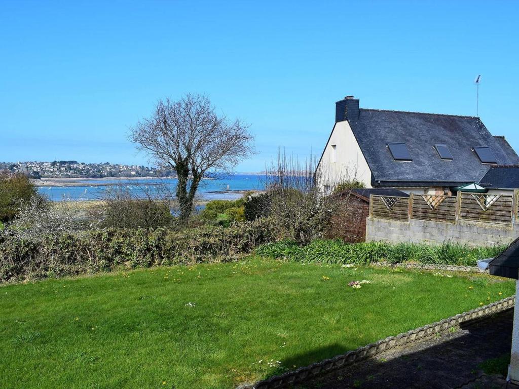 a white barn with a tree and water in the background at Maison Louannec, 5 pièces, 8 personnes - FR-1-368-65 in Louannec