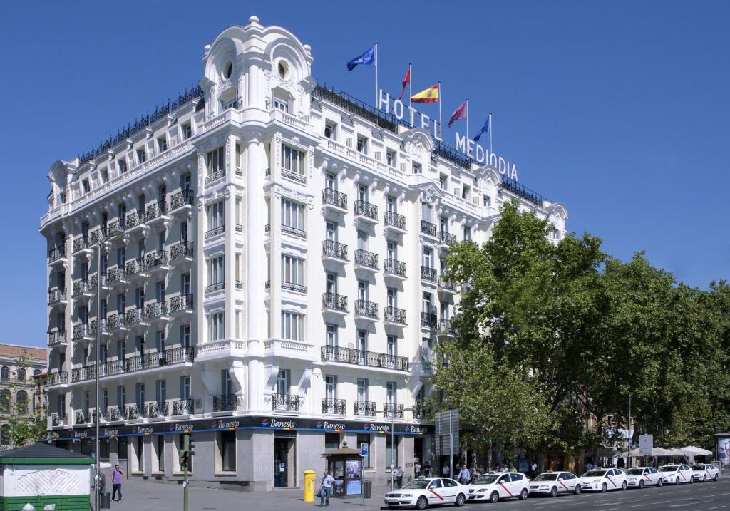 un gran edificio blanco con coches estacionados frente a él en Hotel Mediodia en Madrid