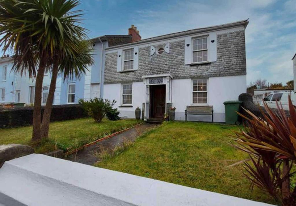 a white house with a palm tree in the yard at Unique 4bed large central Hayle cottage nr St Ives in Hayle