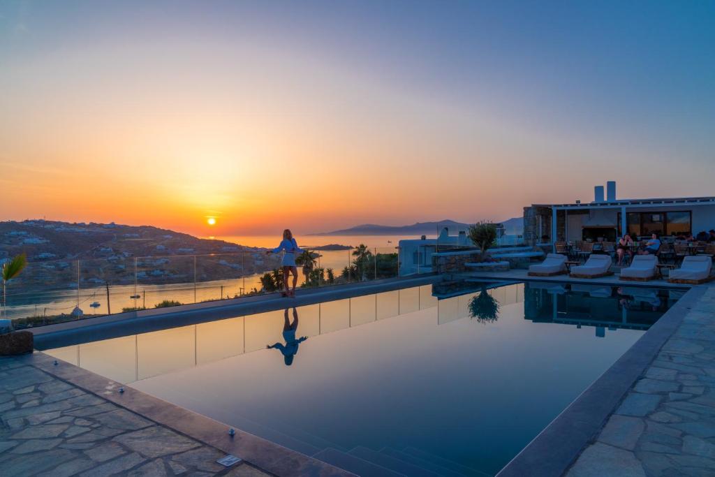 a swimming pool with the sunset in the background at IL Vento Suites in Mikonos