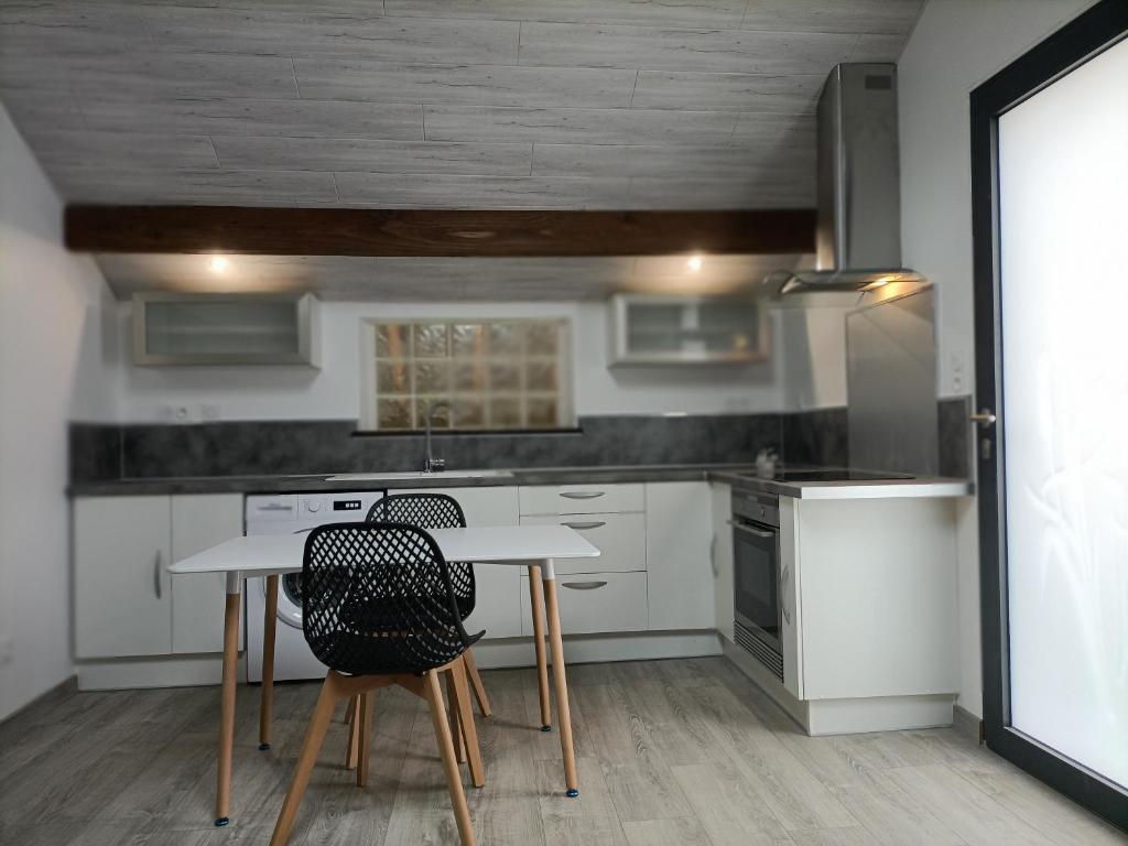 a kitchen with white cabinets and a table and chairs at La clé du Champ in Le Clerjus