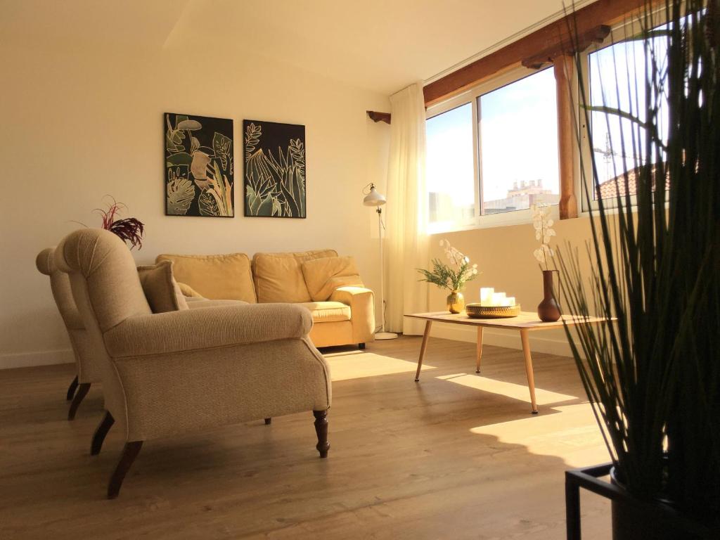 uma sala de estar com um sofá e uma cadeira em Lujoso Apartamento en San Cristobal de la Laguna em La Laguna