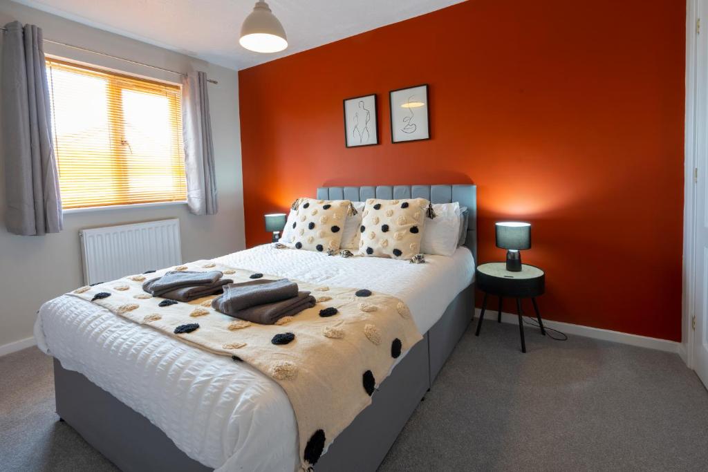 a bedroom with a large bed with an orange wall at Bright & modern 4 bedroom townhouse in Stafford