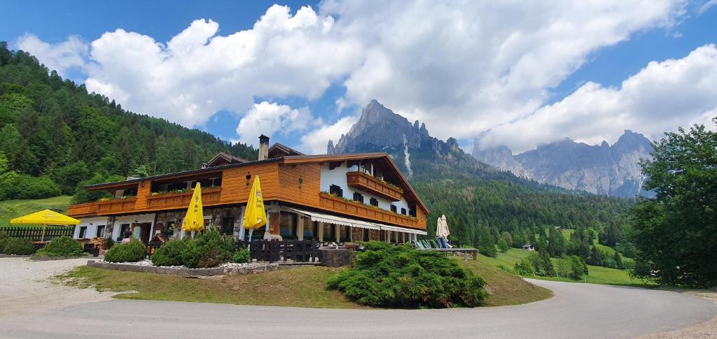 a building with yellow umbrellas in front of a mountain at Chalet Piereni in Fiera di Primiero