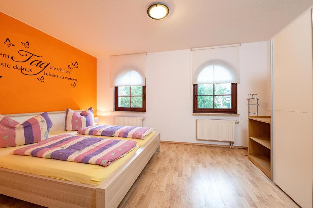 Ferienwohnung Storchennest في باد ليبنستين: غرفة نوم بسريرين وجدار برتقالي
