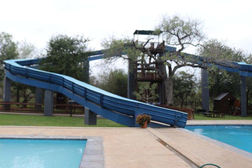 a slide in a swimming pool with a playground at Unogwaja Rest in Marloth Park