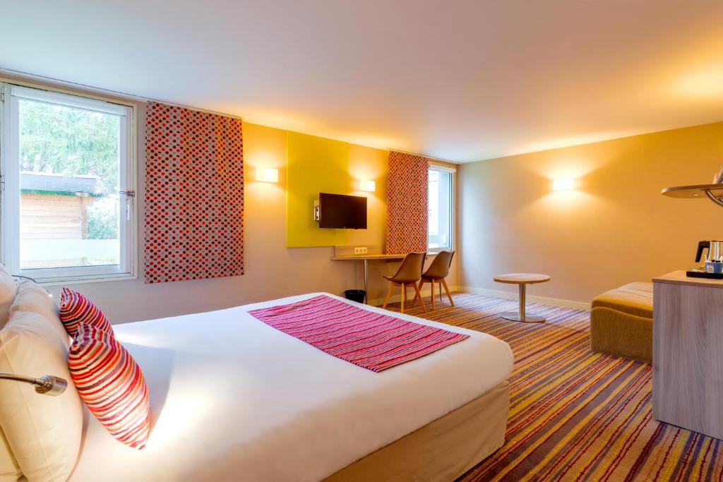 a hotel room with a large bed and a tv at Kyriad Lyon Est - Saint Bonnet De Mure in Saint-Bonnet-de-Mure