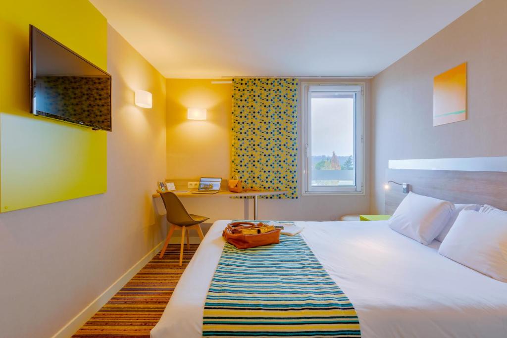 a hotel room with a bed and a desk at Kyriad Lyon Est - Saint Bonnet De Mure in Saint-Bonnet-de-Mure