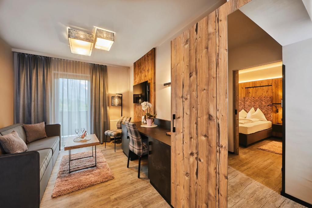 ein Wohnzimmer mit einem Sofa und einem Schreibtisch in einem Zimmer in der Unterkunft Aparthotel Bergland in Söll