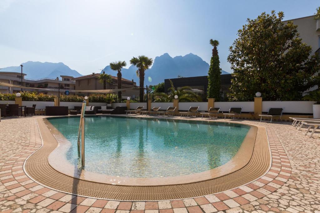 a swimming pool at a resort with mountains in the background at New Garden in Nago-Torbole