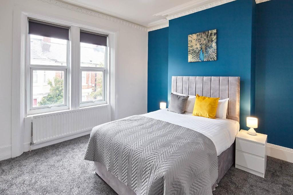 una camera da letto con pareti blu e un letto con cuscini gialli di Host & Stay - 58 Dilston Road a Newcastle upon Tyne