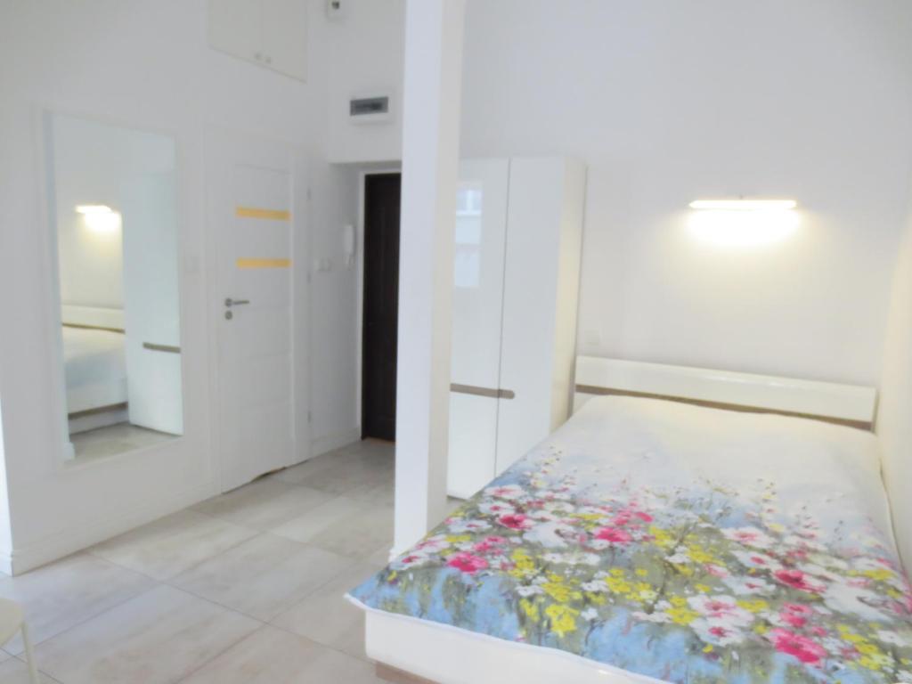 a white bedroom with a bed with flowers on it at Lovely apartment in the heart of the Old Town in Gdańsk