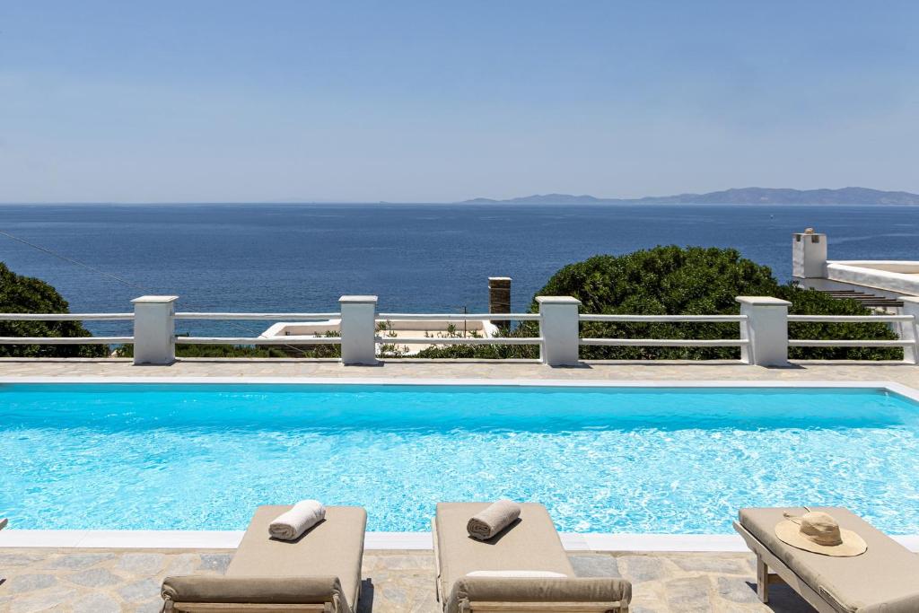 una piscina con due sedie a sdraio e l'oceano di Big Blue Suites & Apartments a Kionia
